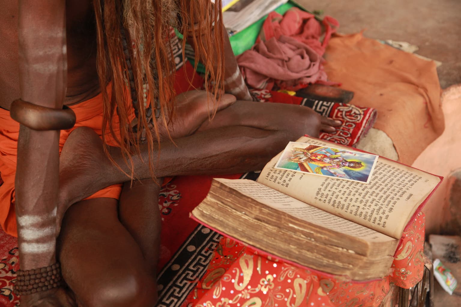 Yogi en contemplation sacrée – Yogi in sacred contemplatioN
De la série Transmutation spirituelle Varanasi (Bénarès), Uttar Pradesh, Inde septentrionale. 2013
In its balance of light, texture, and human presence, this photographic artwork presents the intimate portrait of a yogi sitting on the shore of the Ganga River, reflecting on a sacred Hindu text, and in this way illuminating centuries of spiritual tradition on the ghats of Varanasi, capturing a moment of profound stillness and spiritual immersion. The composition reflects universal themes of contemplation, transformation, and enlightenment, connecting the viewer to both personal and collective dimensions of spiritual devotion.