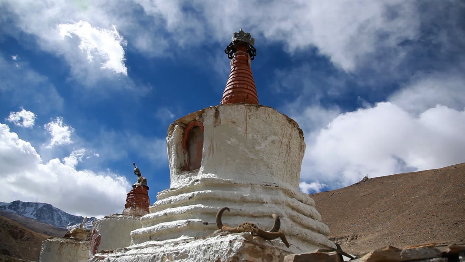 Lac Tso Moriri, Nomadic Zone, Himalayan Plateau, Northern India – 2013
This photograph depicts a whitewashed chorten, which is a type of Buddhist stupa, beneath an expansive Himalayan sky at Tso Moriri, a remote lake region inhabited by nomadic communities. The work captures the interplay of monumental natural forms and sacred architecture, evoking a sense of spiritual expansion within a vast rug landscape.